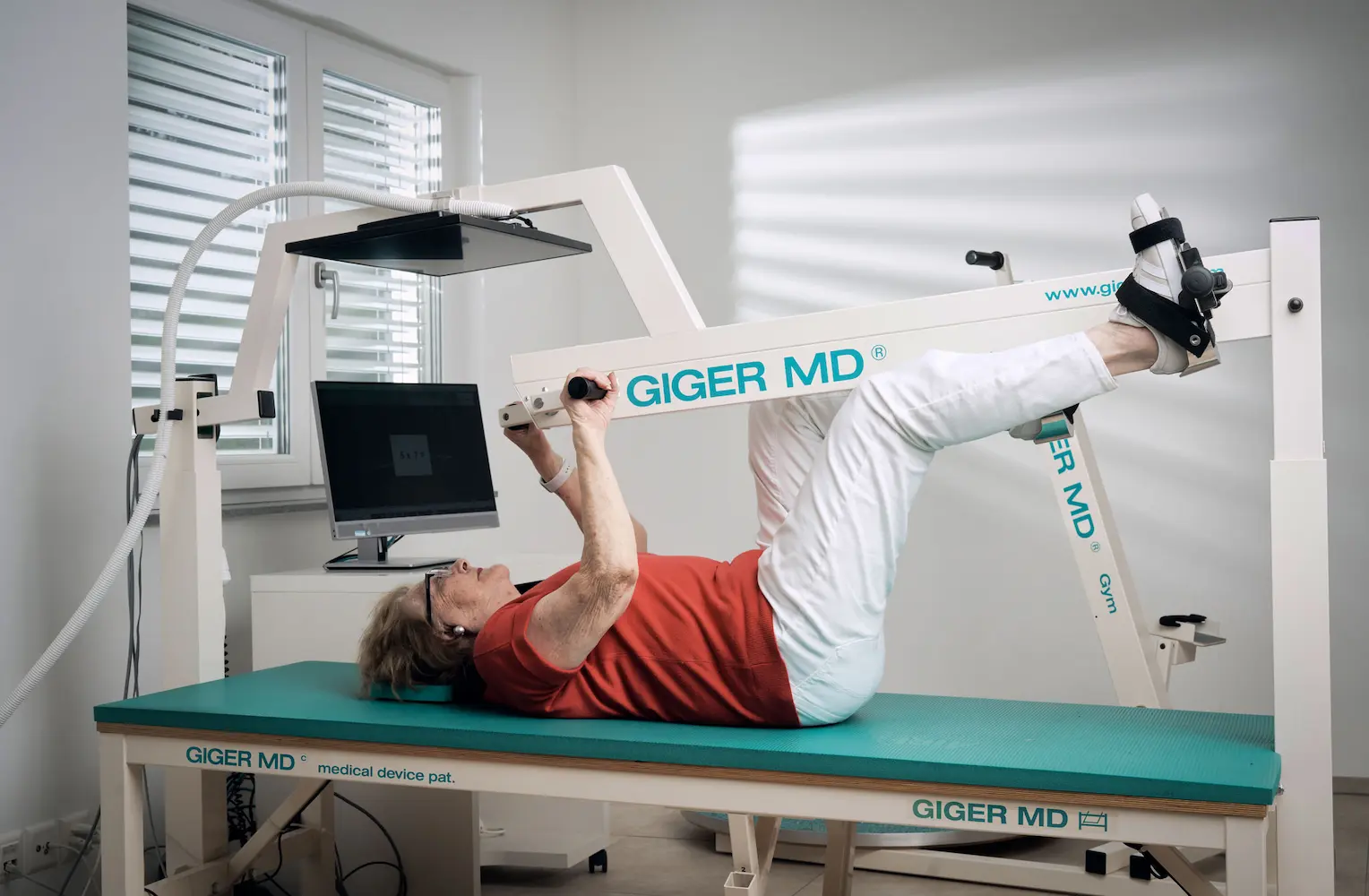 Seniorin trainiert bei Parkinson koordinierte Arm- und Beinbewegungen auf dem GIGER MD Therapiegerät
